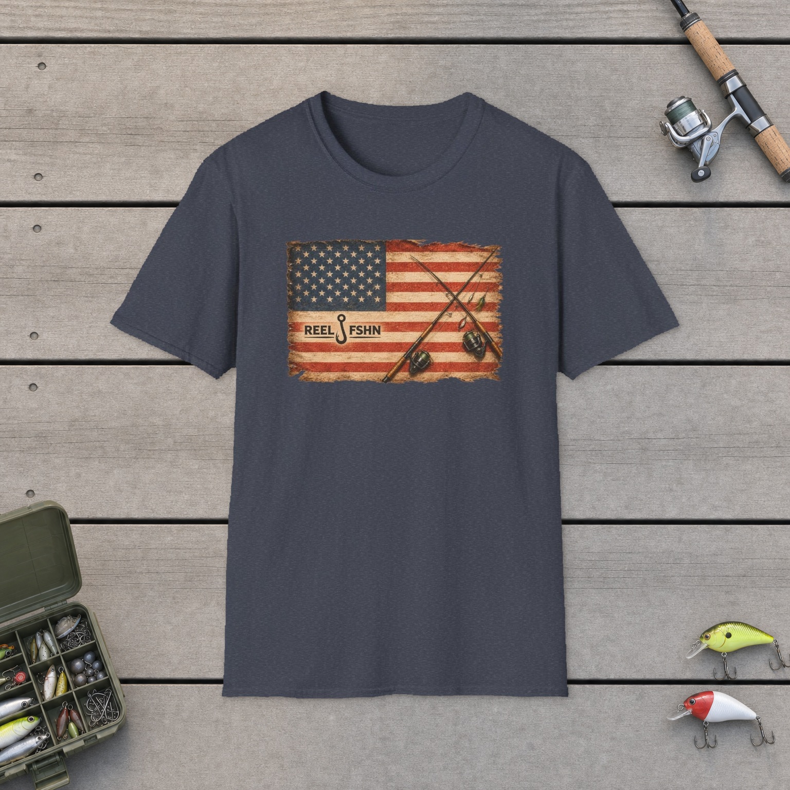 American Flag With Two Rods T-Shirt on a wooden dock with a fishing rod, reel, tackle box, and two lures