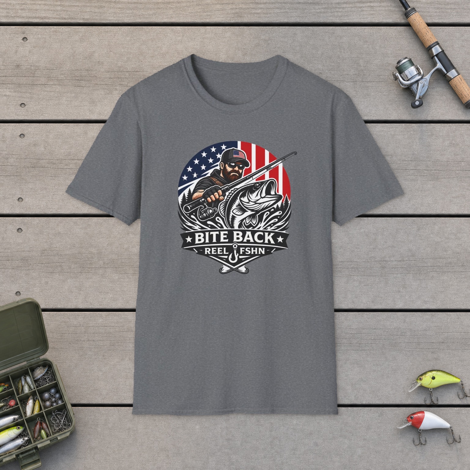 Bite Back T-Shirt on a wooden dock with a fishing rod, reel, tackle box, and two lures