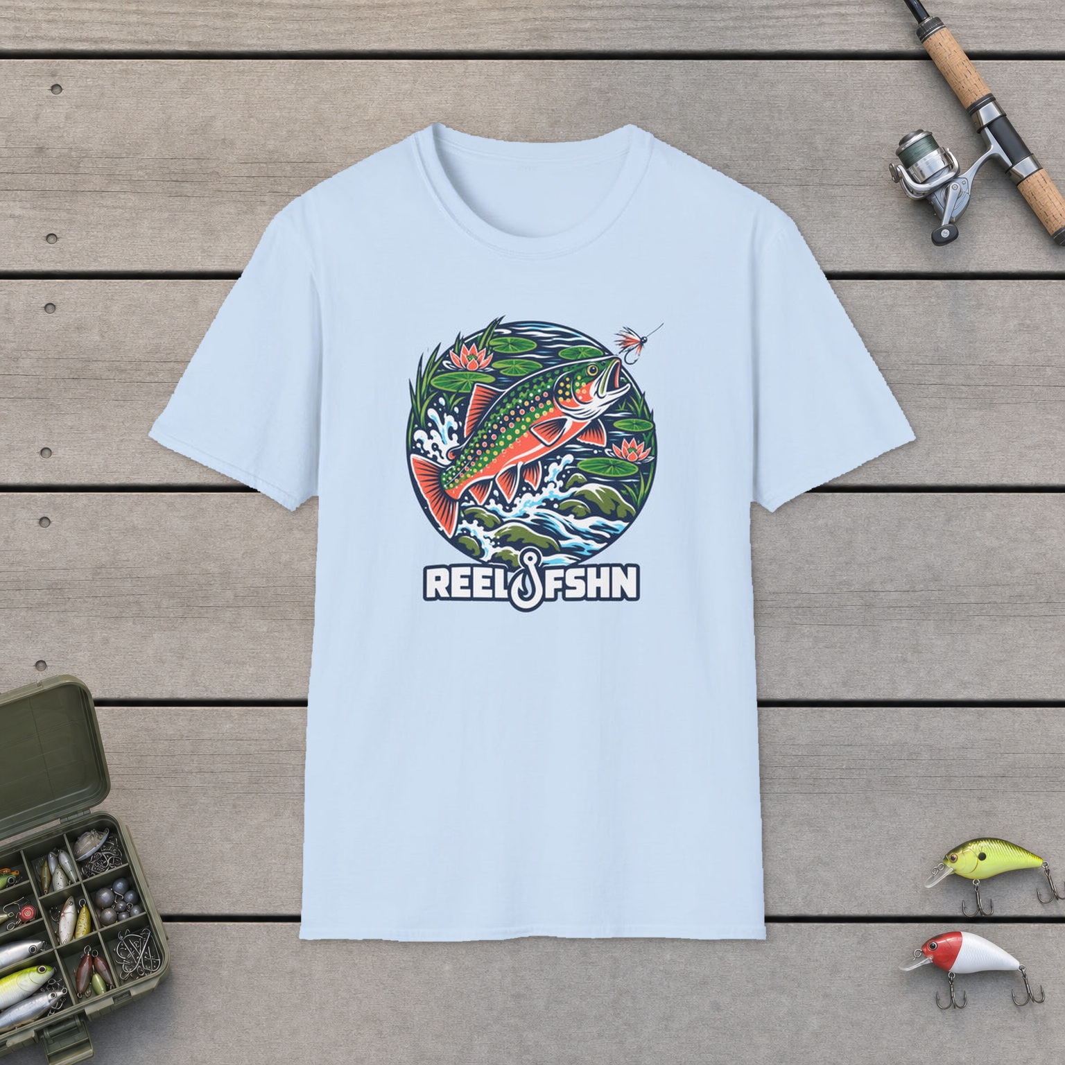 Brook Trout T-Shirt on a wooden dock with a fishing rod, reel, tackle box, and two lures