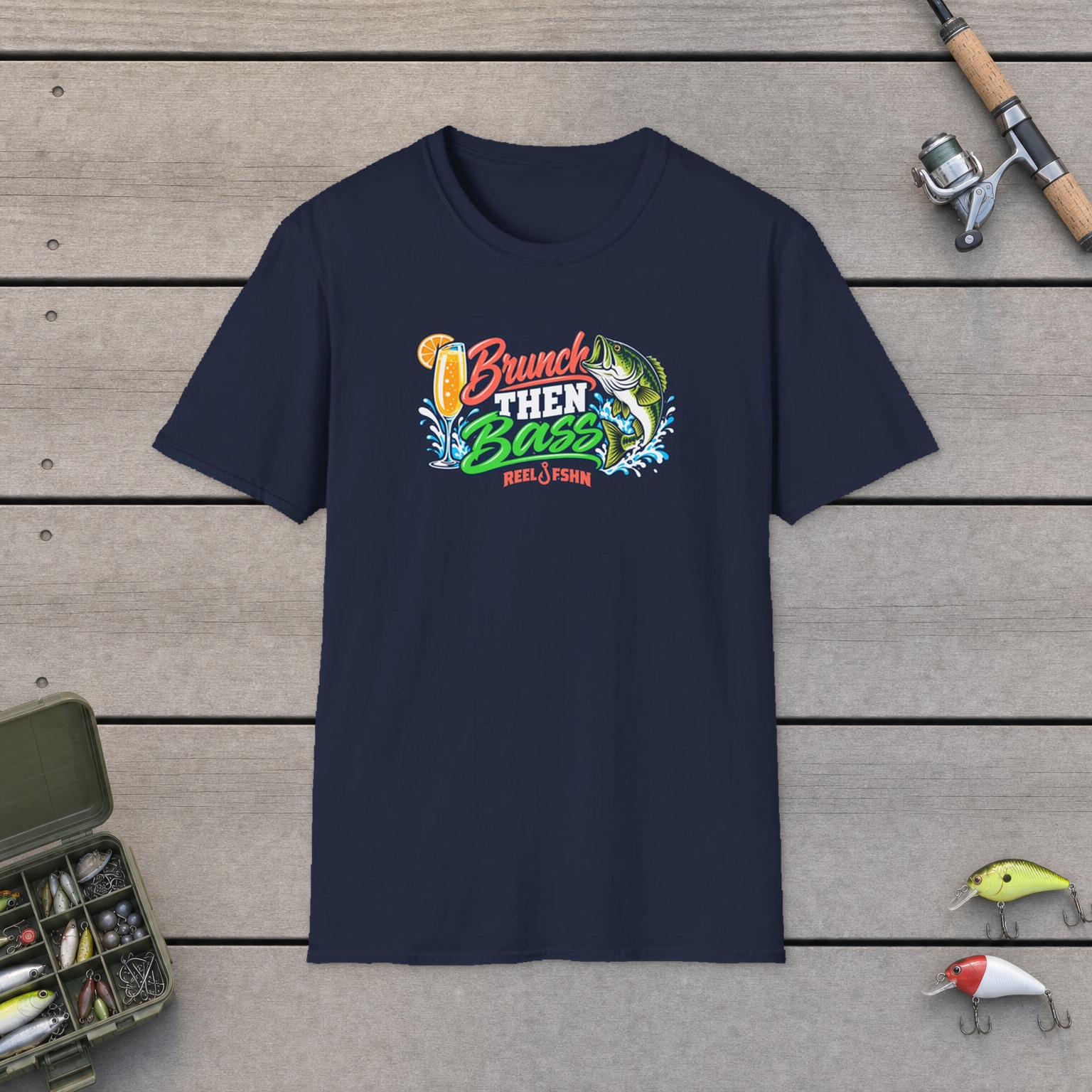 Brunch Then Bass T-Shirt on a wooden dock with a fishing rod, reel, tackle box, and two lures