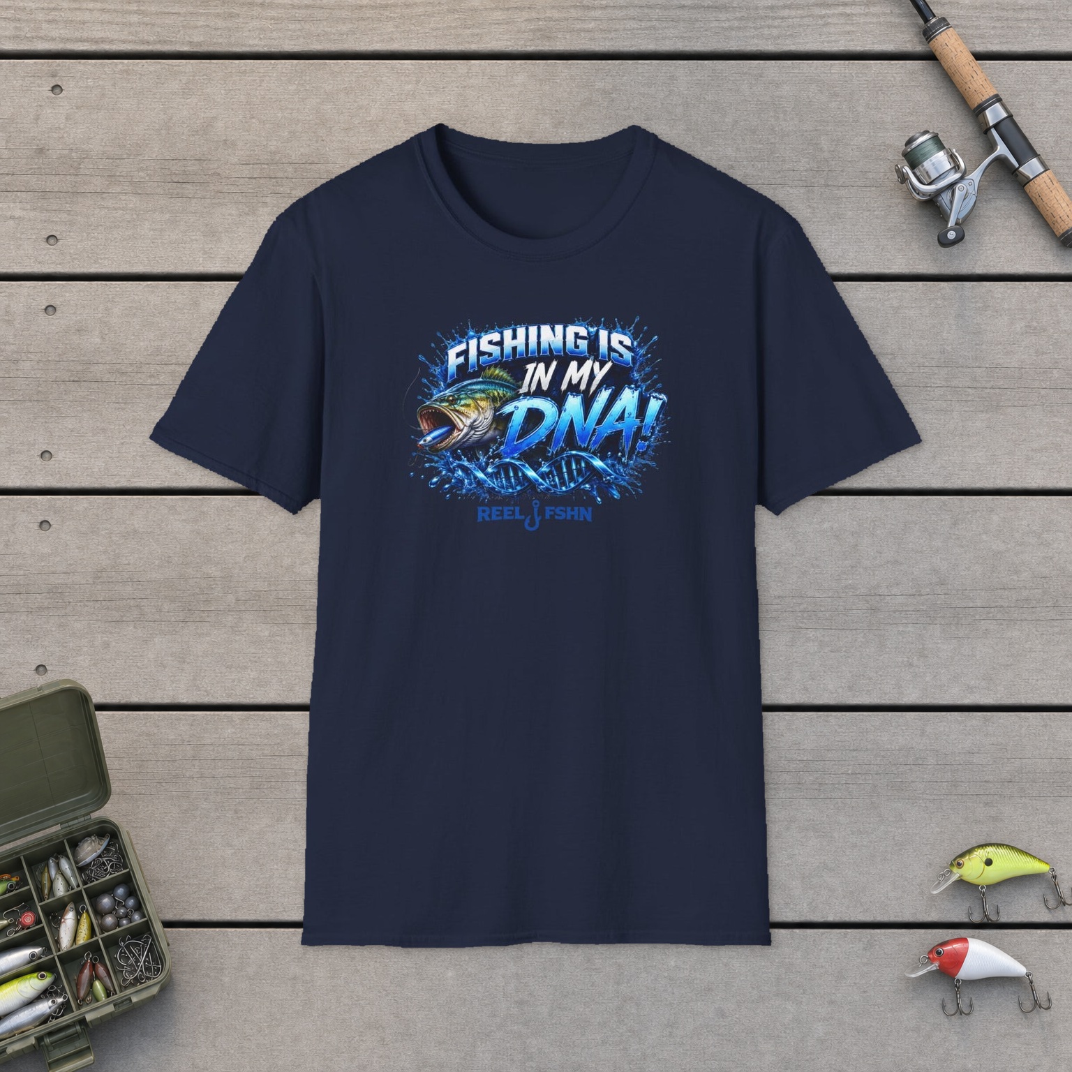 Fishing Is In My DNA with Bass T-Shirt on a wooden dock with a fishing rod, reel, tackle box, and two lures