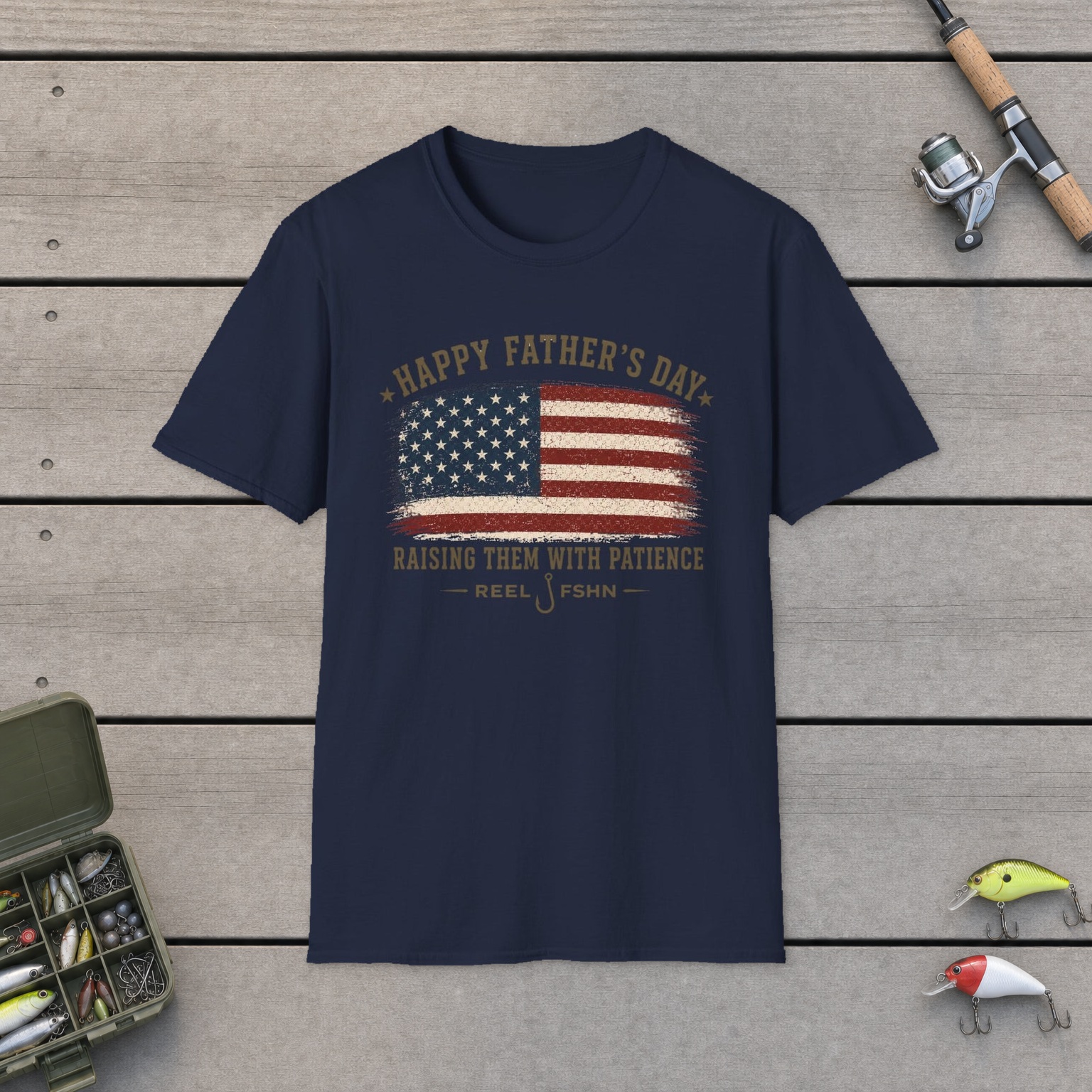 Happy Father's Day Raising Them With Patience T-Shirt on a wooden dock with a fishing rod, reel, tackle box, and two lures