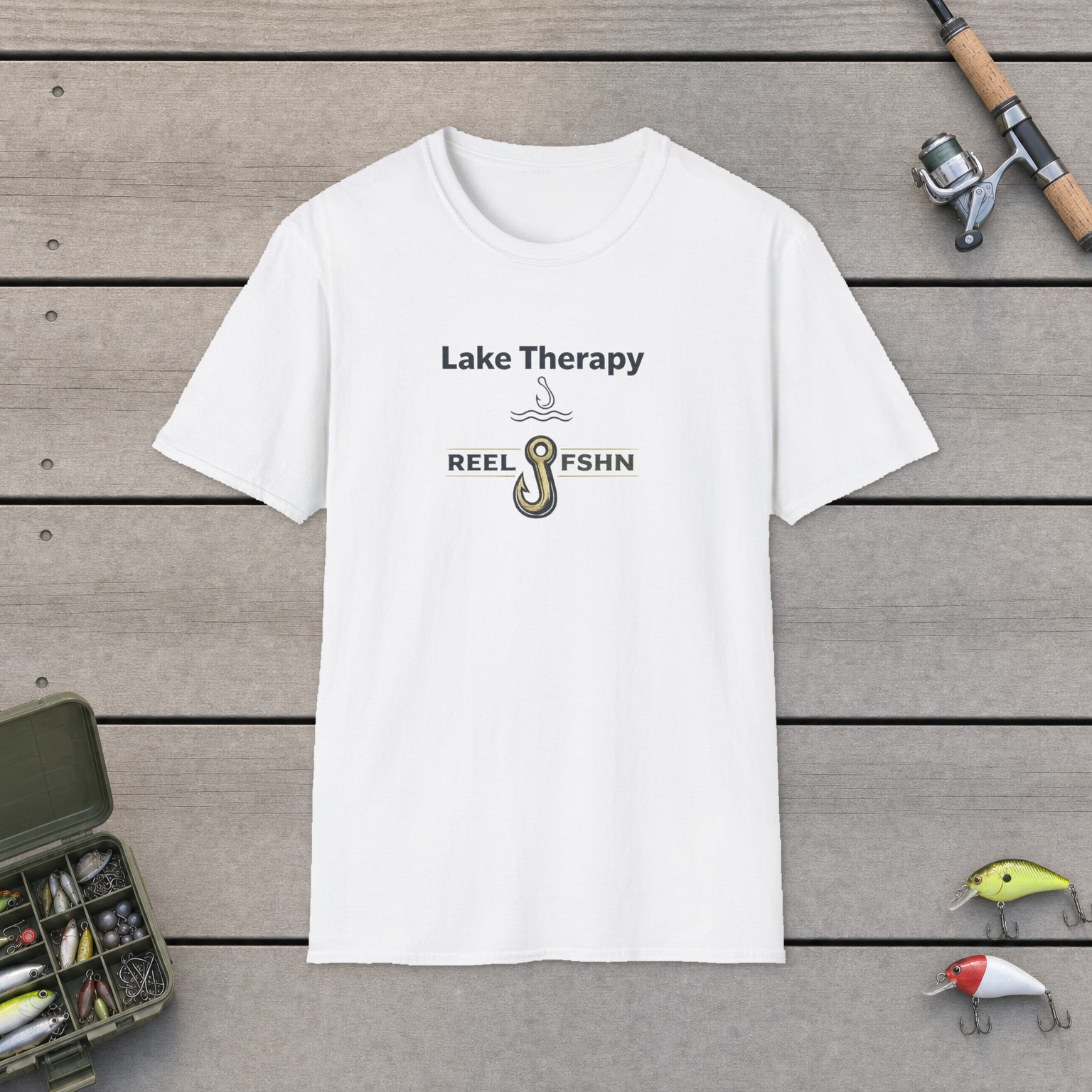 Lake Therapy T-Shirt on a wooden dock with a fishing rod, reel, tackle box, and two lures