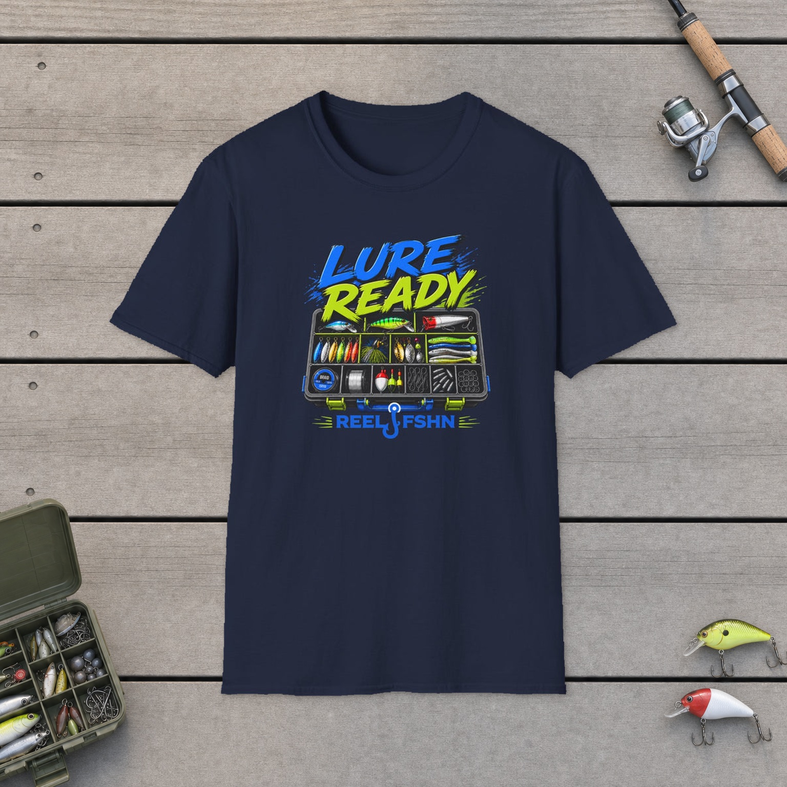 Lure Ready Tacklebox  T-Shirt on a wooden dock with a fishing rod, reel, tackle box, and two lures