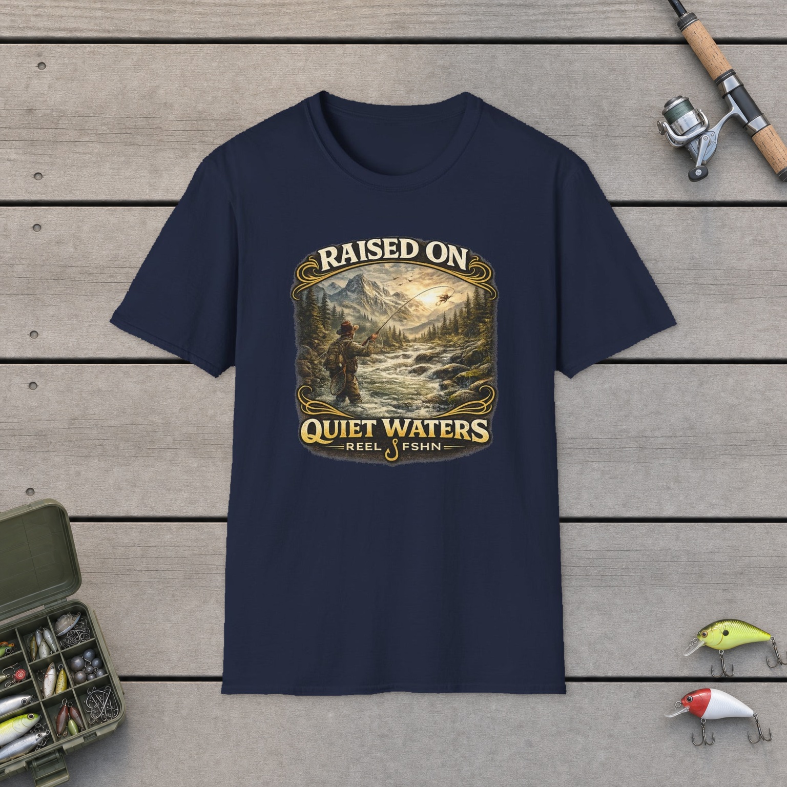 Raised On Quiet Waters T-Shirt on a wooden dock with a fishing rod, reel, tackle box, and two lures