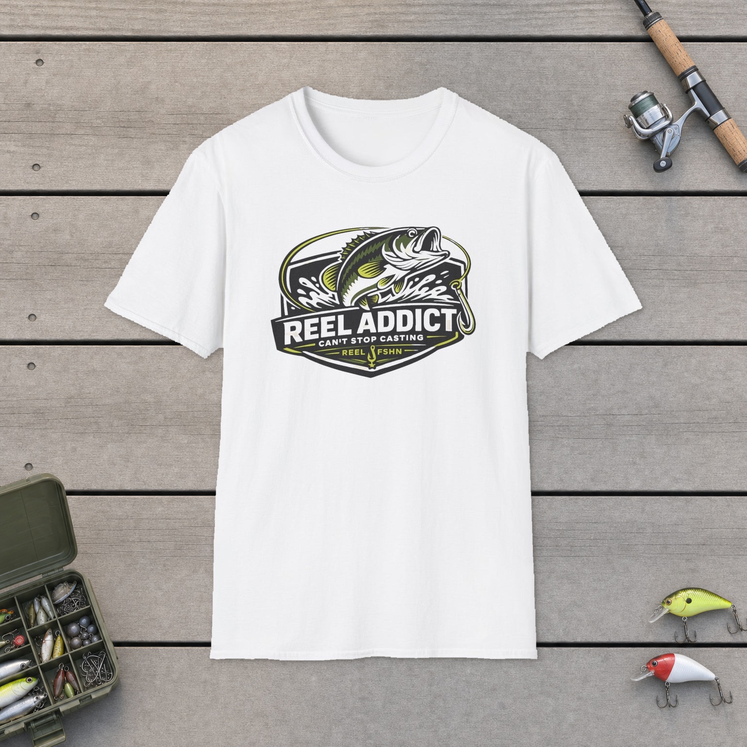 Reel Addict Can't Stop Casting T-Shirt on a wooden dock with a fishing rod, reel, tackle box, and two lures