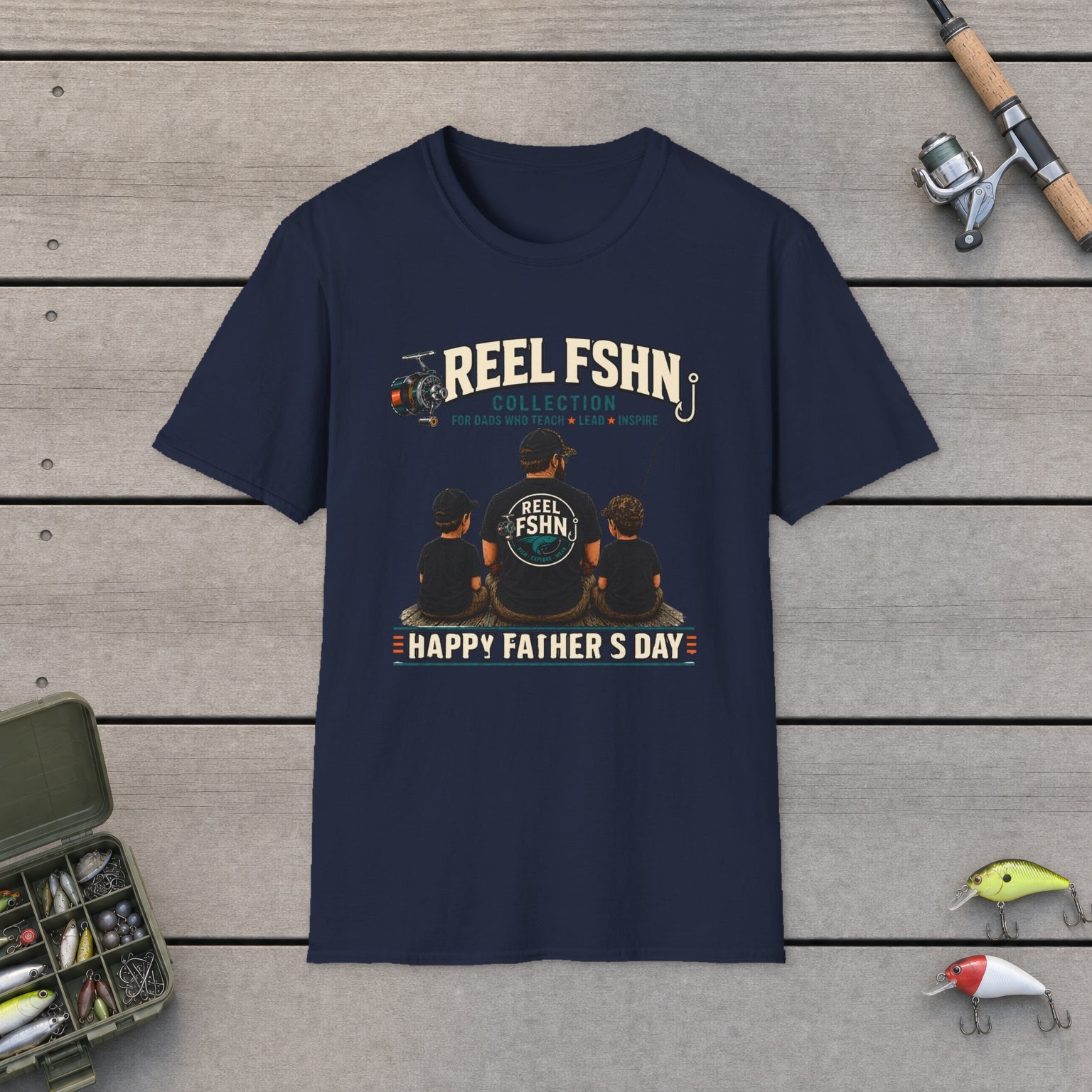 REEL FSHN Happy Father's Day T-Shirt on a wooden dock with a fishing rod, reel, tackle box, and two lures