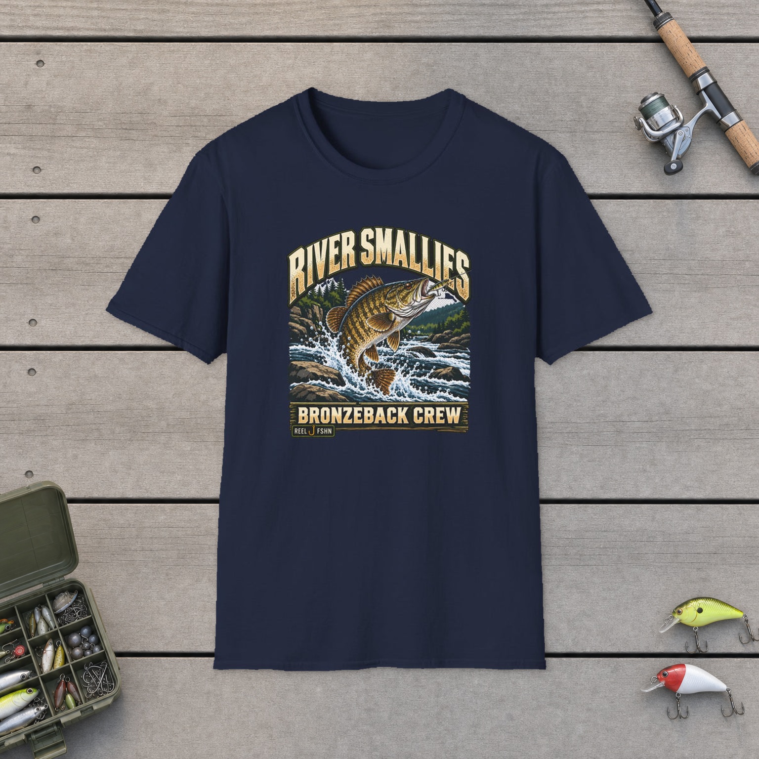 River Smallies T-Shirt on a wooden dock with a fishing rod, reel, tackle box, and two lures