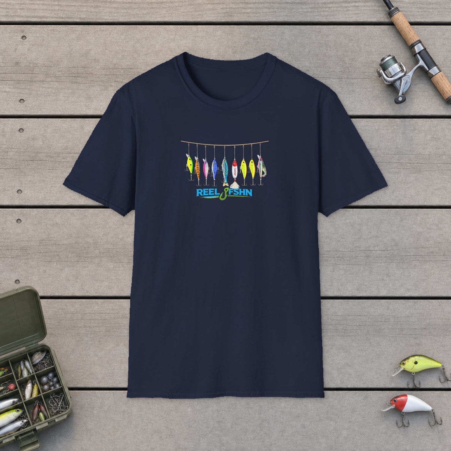 String Of Fishing Lures T-Shirt on a wooden dock with a fishing rod, reel, tackle box, and two lures
