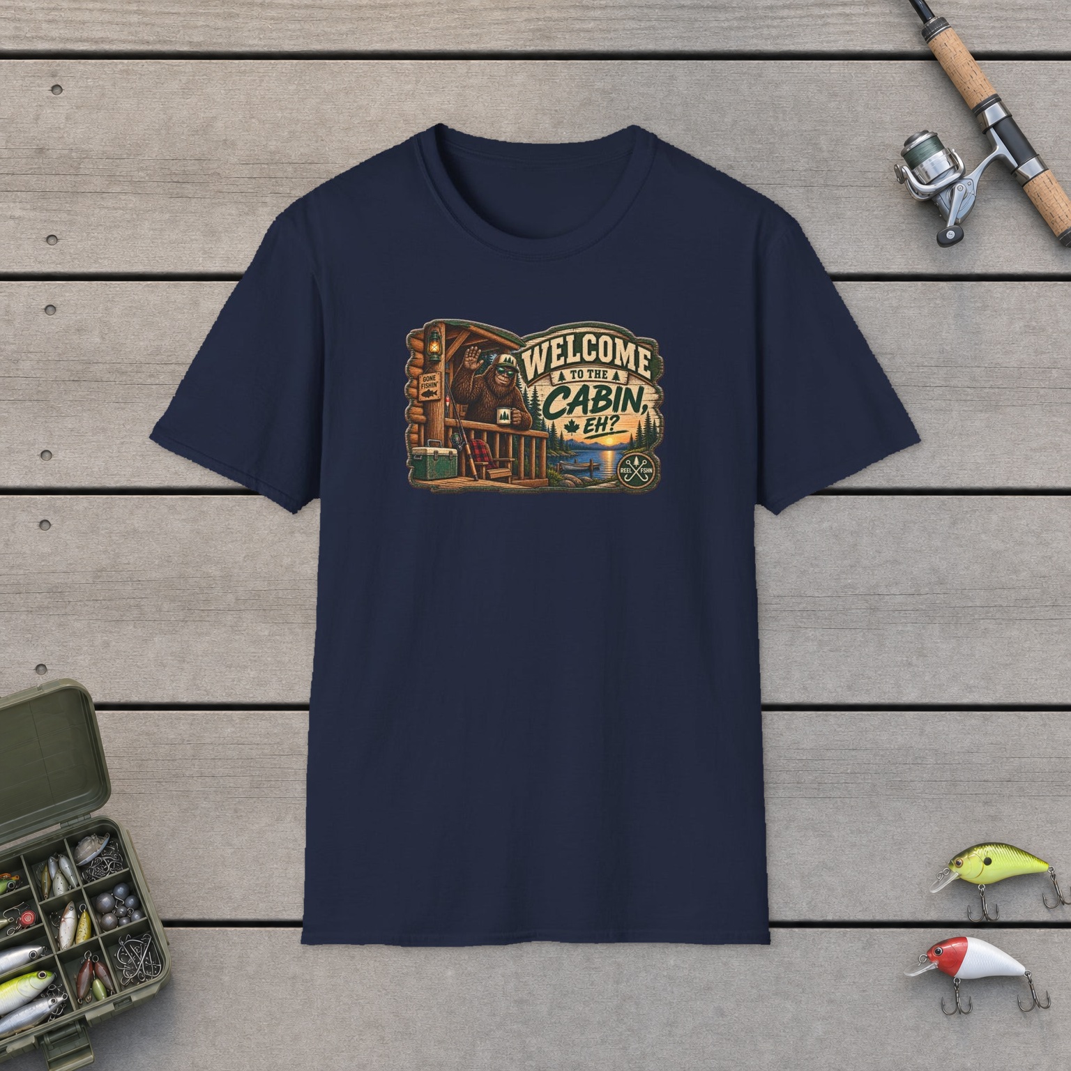 Welcome To The Cabin, EH? T-Shirt on a wooden dock with a fishing rod, reel, tackle box, and two lures