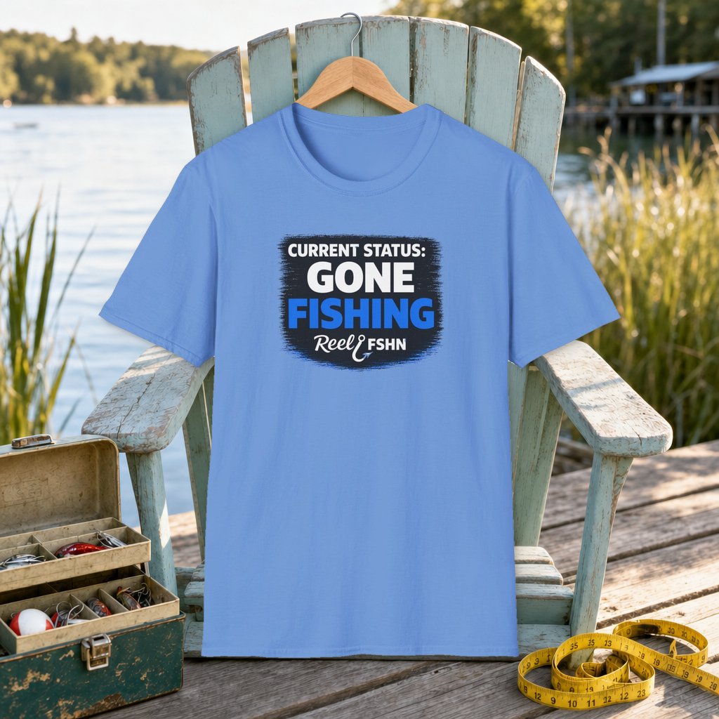 Current Status Gone Fishing T-Shirt on a hanger on a seafoam fishing chair beside a lake, tackle box, and measuring tape