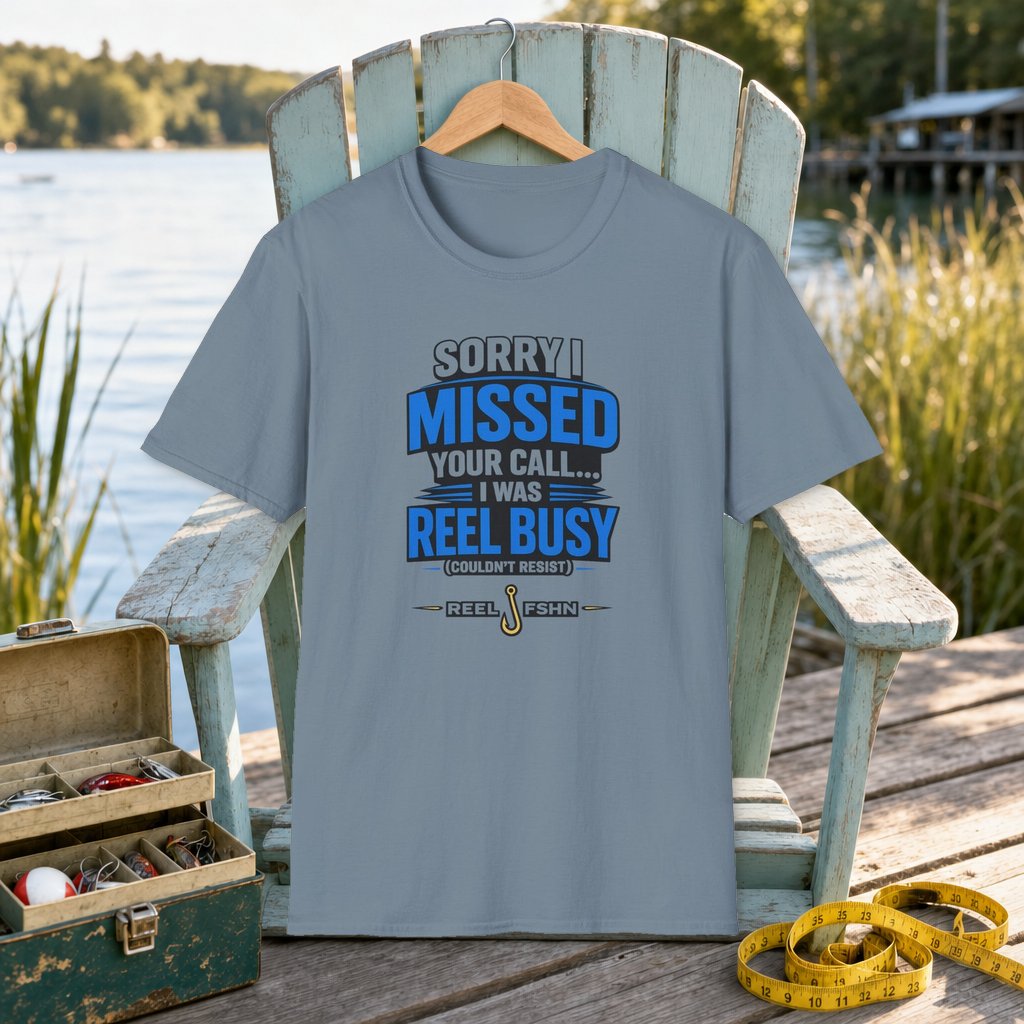 Sorry I Missed Your Call I Was REEL Busy T-Shirt on a hanger on a seafoam fishing chair beside a lake, tackle box, and measuring tape