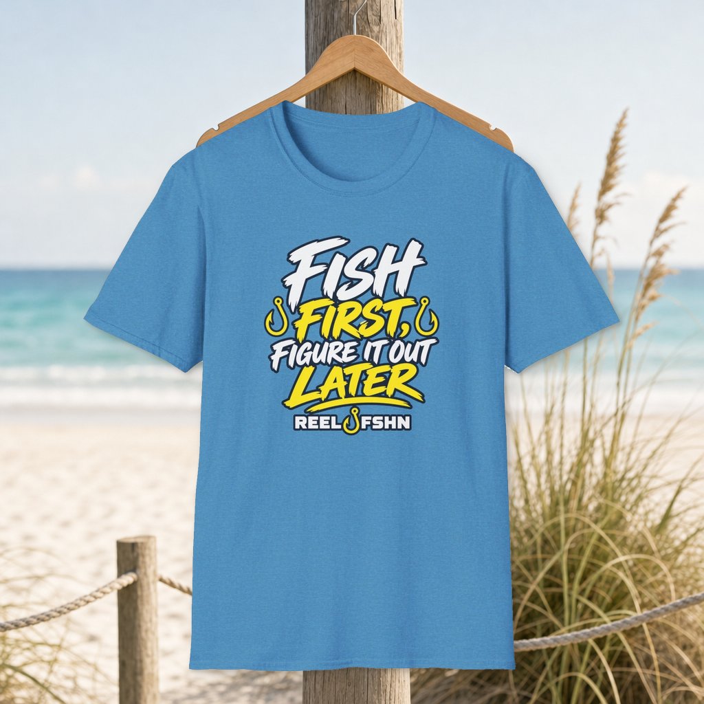 Fish First, Figure It Out Later T-Shirt on a hanger beside a sandy beach and turquoise coastal water