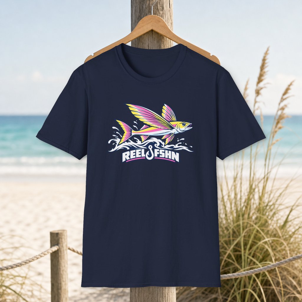 Flying Fish T-Shirt on a hanger beside a sandy beach and turquoise coastal water