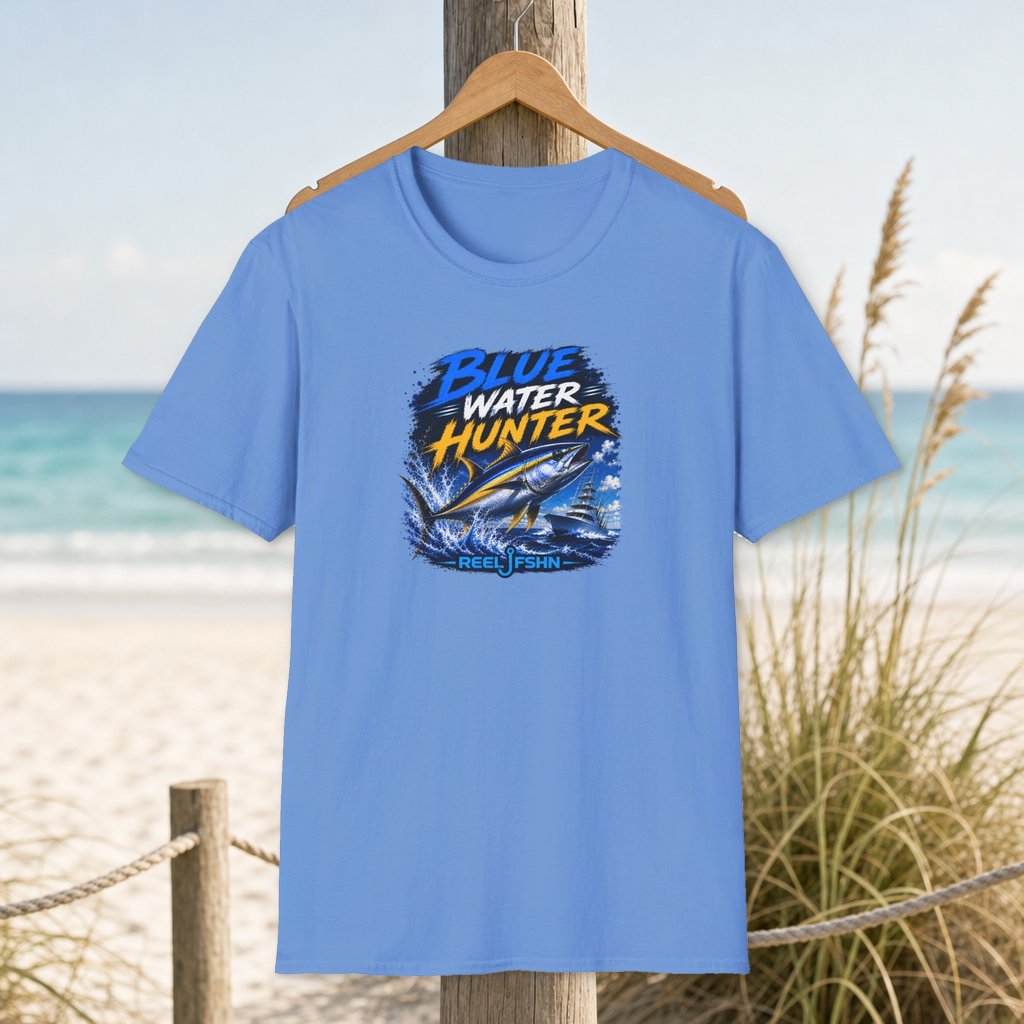 Blue Water Hunter T-Shirt on a hanger beside a sandy beach and turquoise coastal water