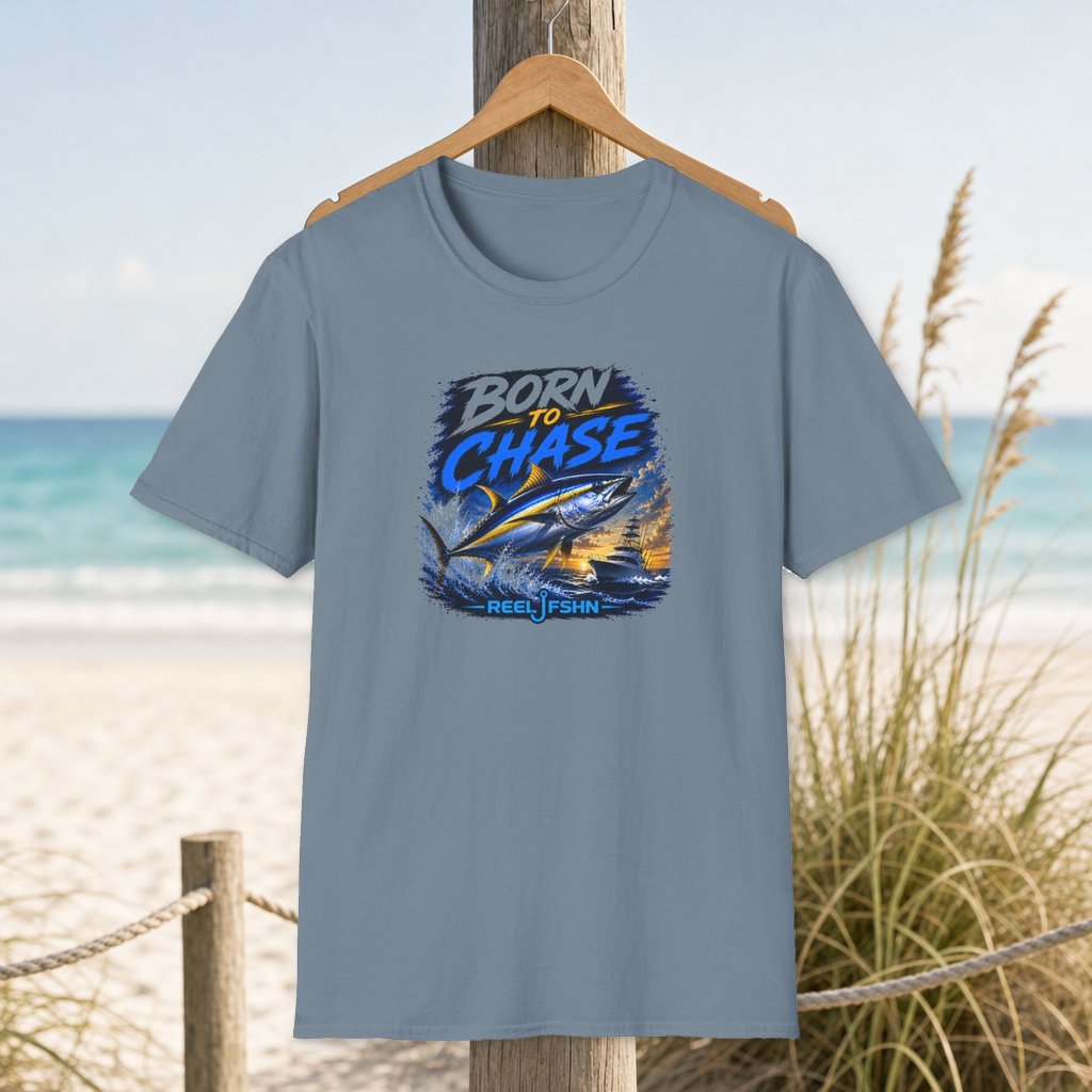 Born To Chase T-Shirt on a hanger beside a sandy beach and turquoise coastal water