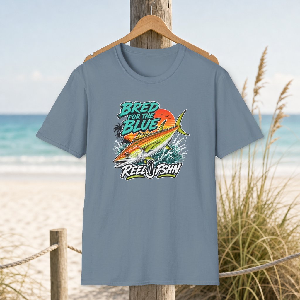Bred For The Blue T-Shirt on a hanger beside a sandy beach and turquoise coastal water