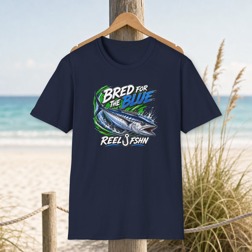 Bred For The Blue T-Shirt on a hanger beside a sandy beach and turquoise coastal water