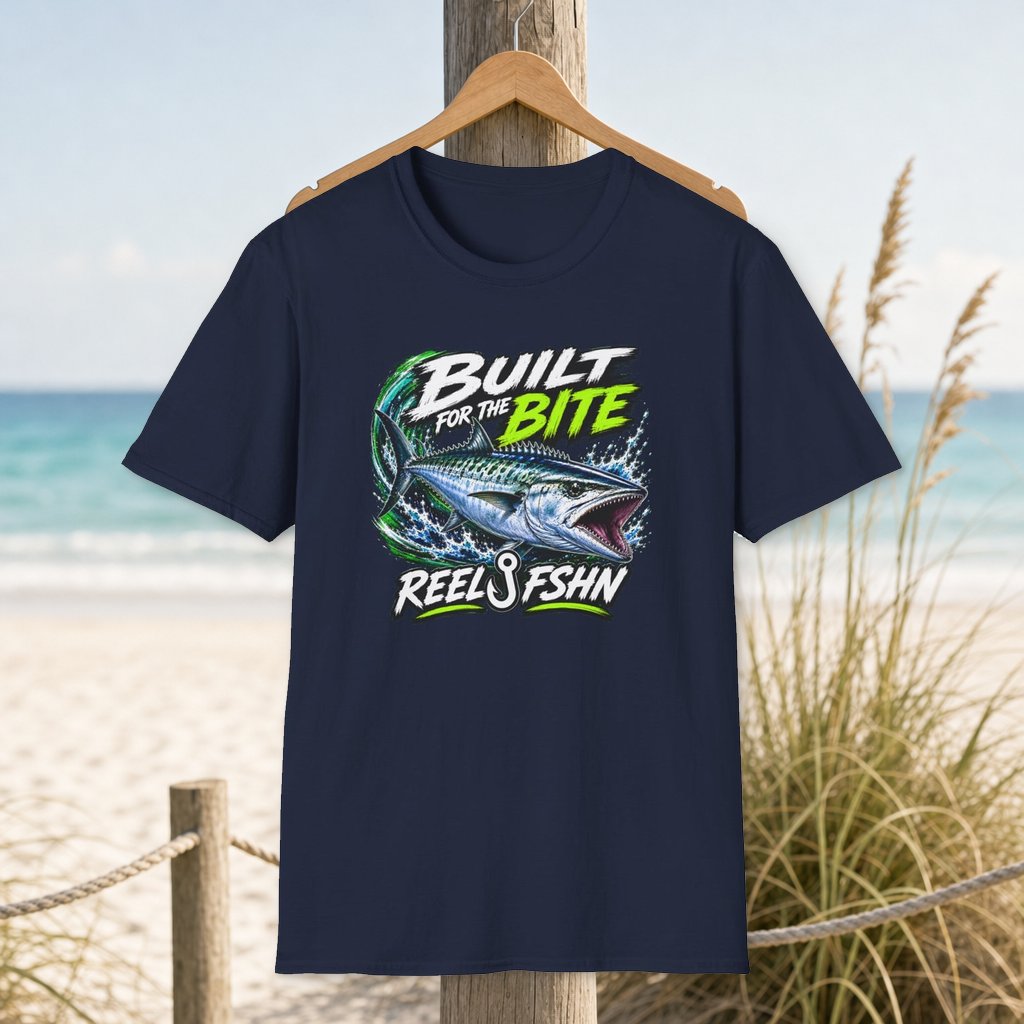 Built For The Bite T-Shirt on a hanger beside a sandy beach and turquoise coastal water