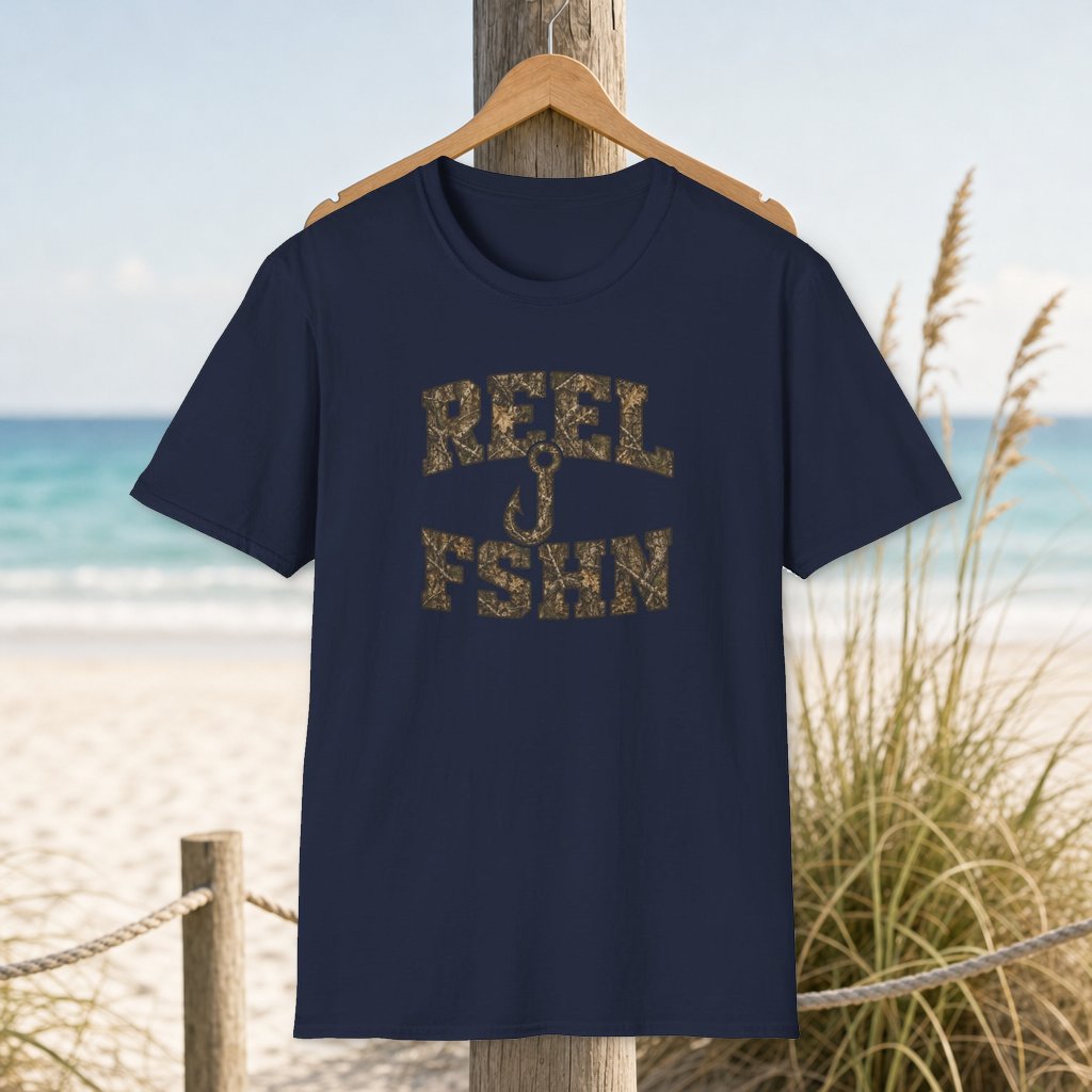 Camo Hook Mashup T-Shirt on a hanger beside a sandy beach and turquoise coastal water