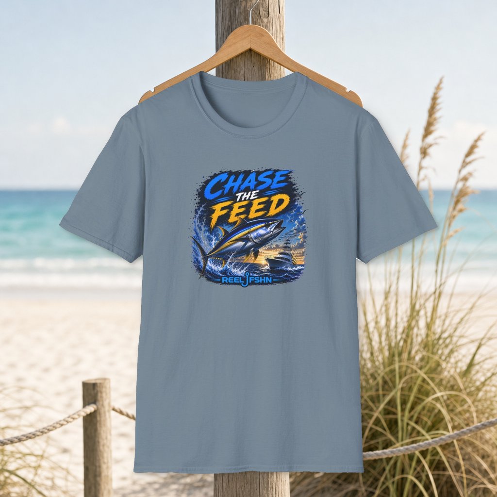 Chase The Feed T-Shirt on a hanger beside a sandy beach and turquoise coastal water