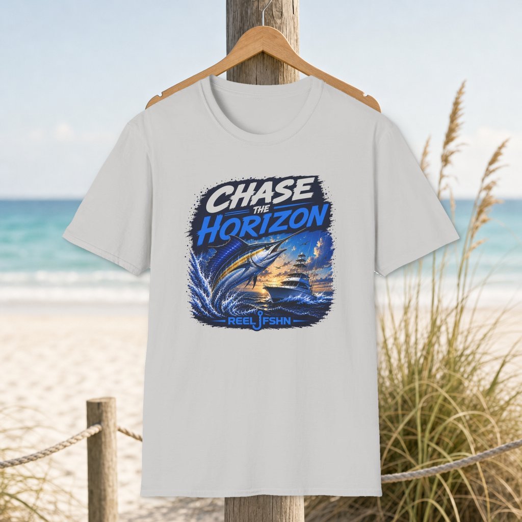 Chase The Horizon T-Shirt on a hanger beside a sandy beach and turquoise coastal water