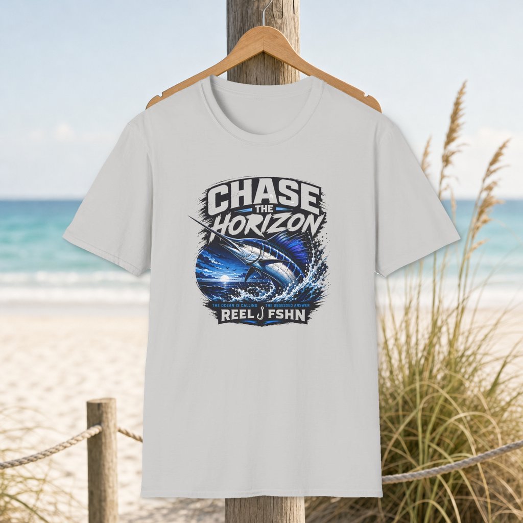 Chase The Horizon Marlin T-Shirt on a hanger beside a sandy beach and turquoise coastal water