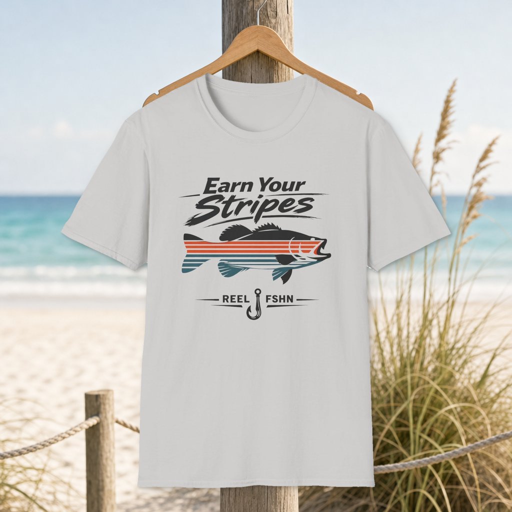 Earn Your Stripes T-Shirt on a hanger beside a sandy beach and turquoise coastal water