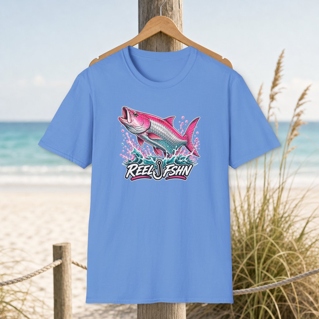 Flamingo Pink Tarpon T-Shirt on a hanger beside a sandy beach and turquoise coastal water