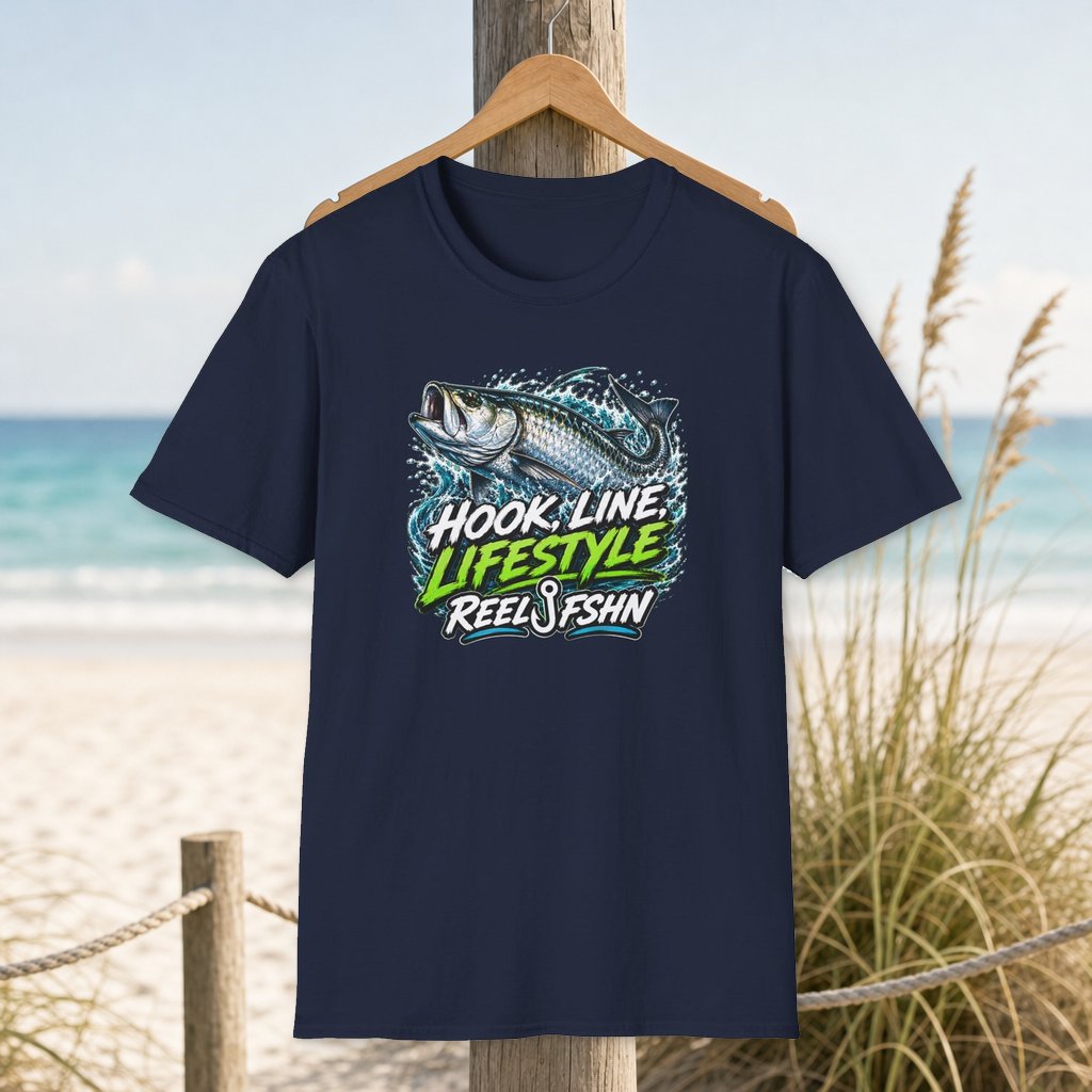 Hook, Line, Lifestyle T-Shirt on a hanger beside a sandy beach and turquoise coastal water