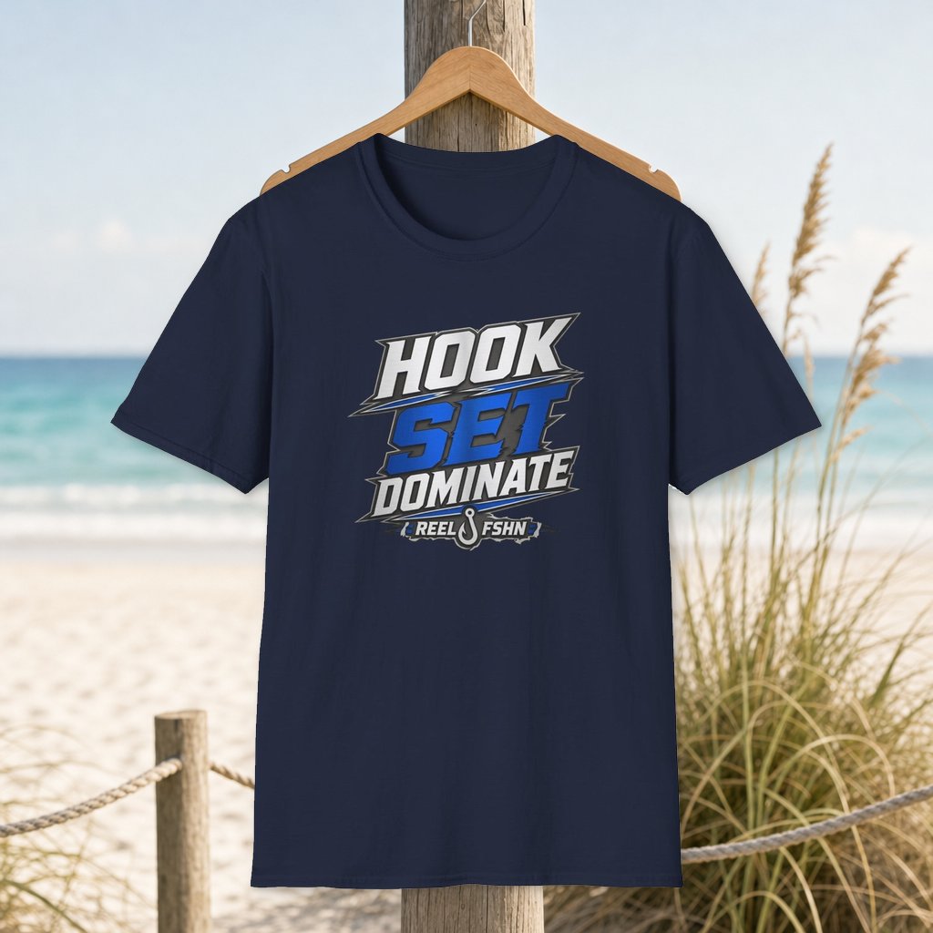 Hook Set Dominate  T-Shirt on a hanger beside a sandy beach and turquoise coastal water