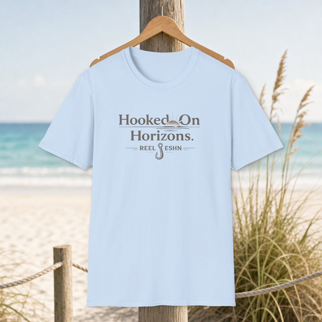 Hooked On Horizons T-Shirt on a hanger beside a sandy beach and turquoise coastal water