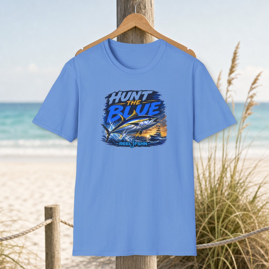 Hunt The Blue T-Shirt on a hanger beside a sandy beach and turquoise coastal water