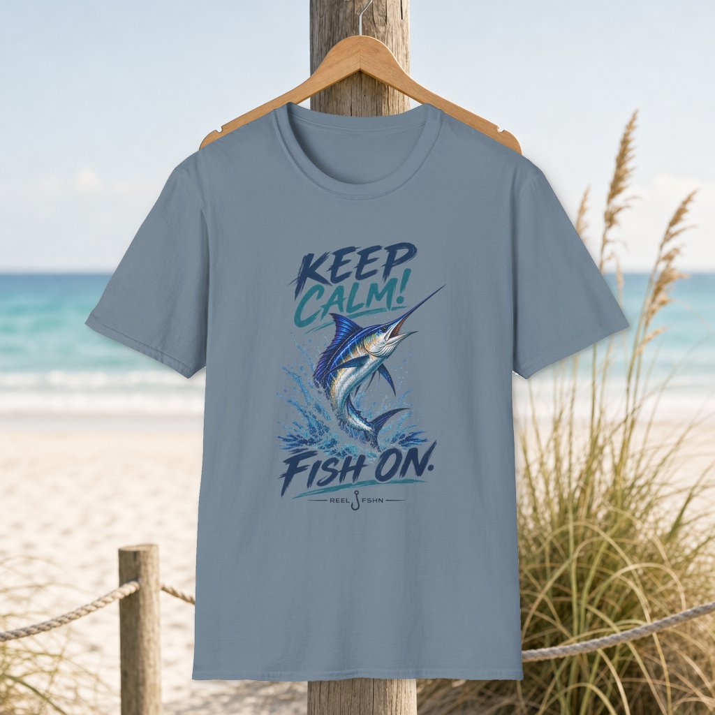 Keep Calm! Fish On. T-Shirt on a hanger beside a sandy beach and turquoise coastal water