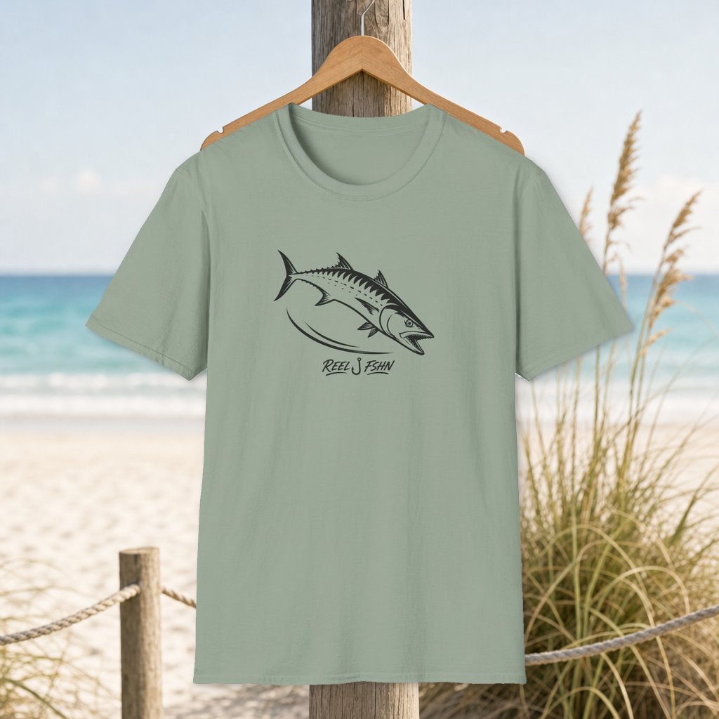 Kingfish Cutline T-Shirt on a hanger beside a sandy beach and turquoise coastal water
