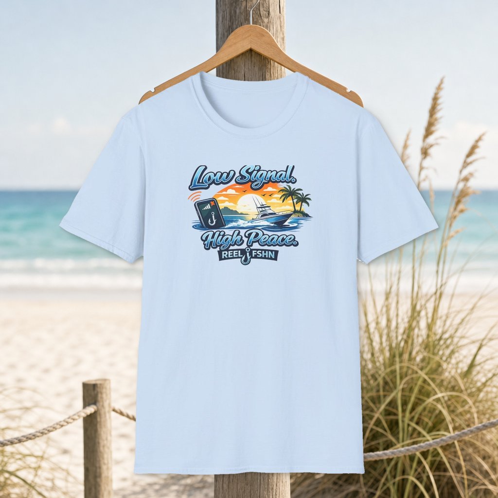 Low Signal High Peace T-Shirt on a hanger beside a sandy beach and turquoise coastal water