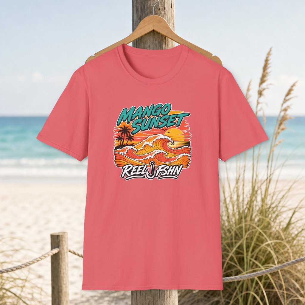 Mango Sunset T-Shirt on a hanger beside a sandy beach and turquoise coastal water