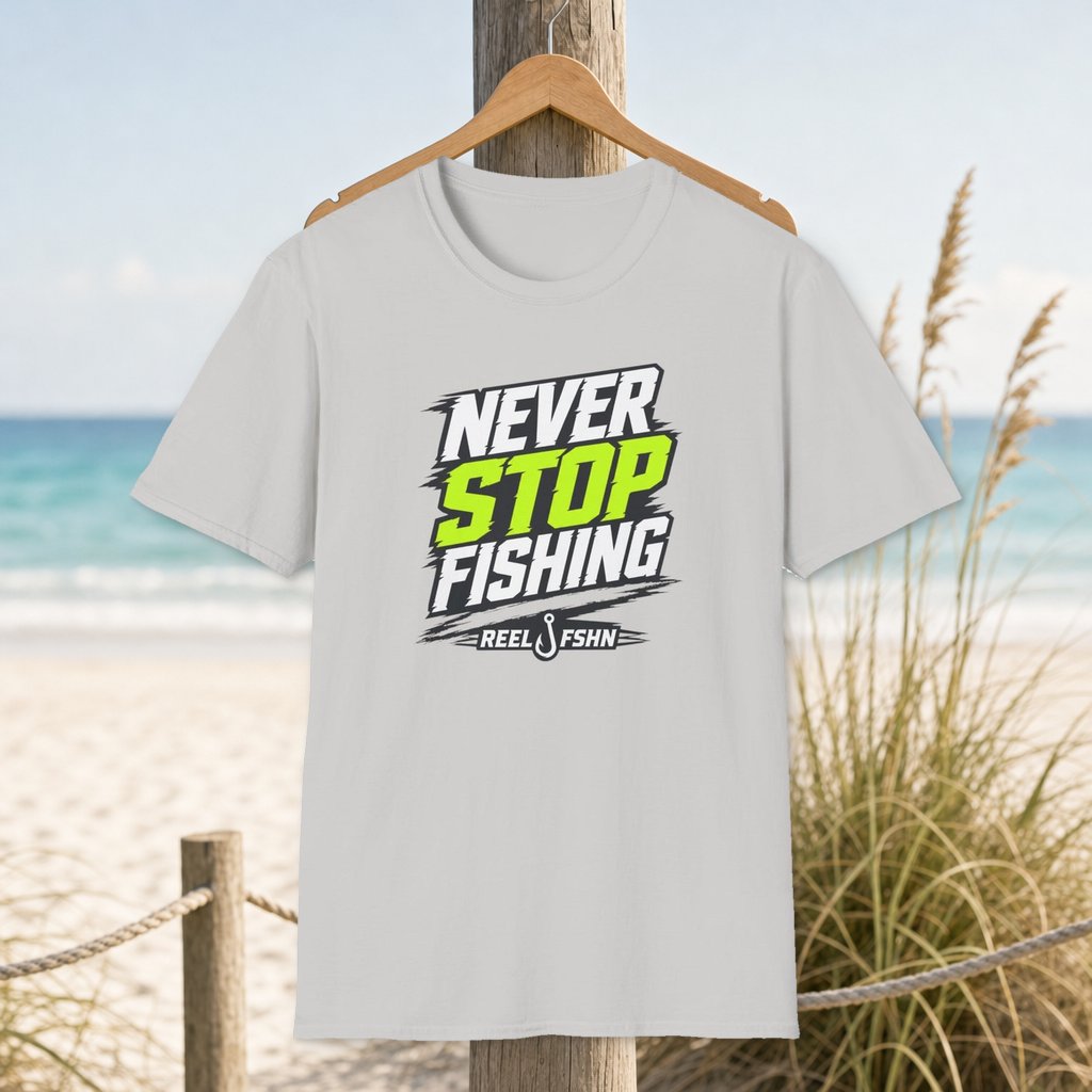 Never Stop Fishing T-Shirt on a hanger beside a sandy beach and turquoise coastal water
