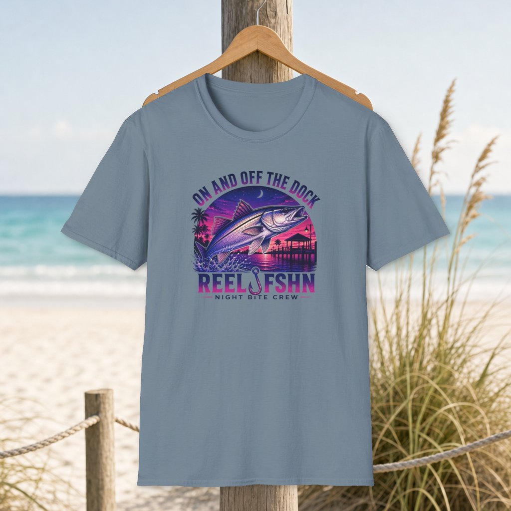 On And Off The Dock T-Shirt on a hanger beside a sandy beach and turquoise coastal water