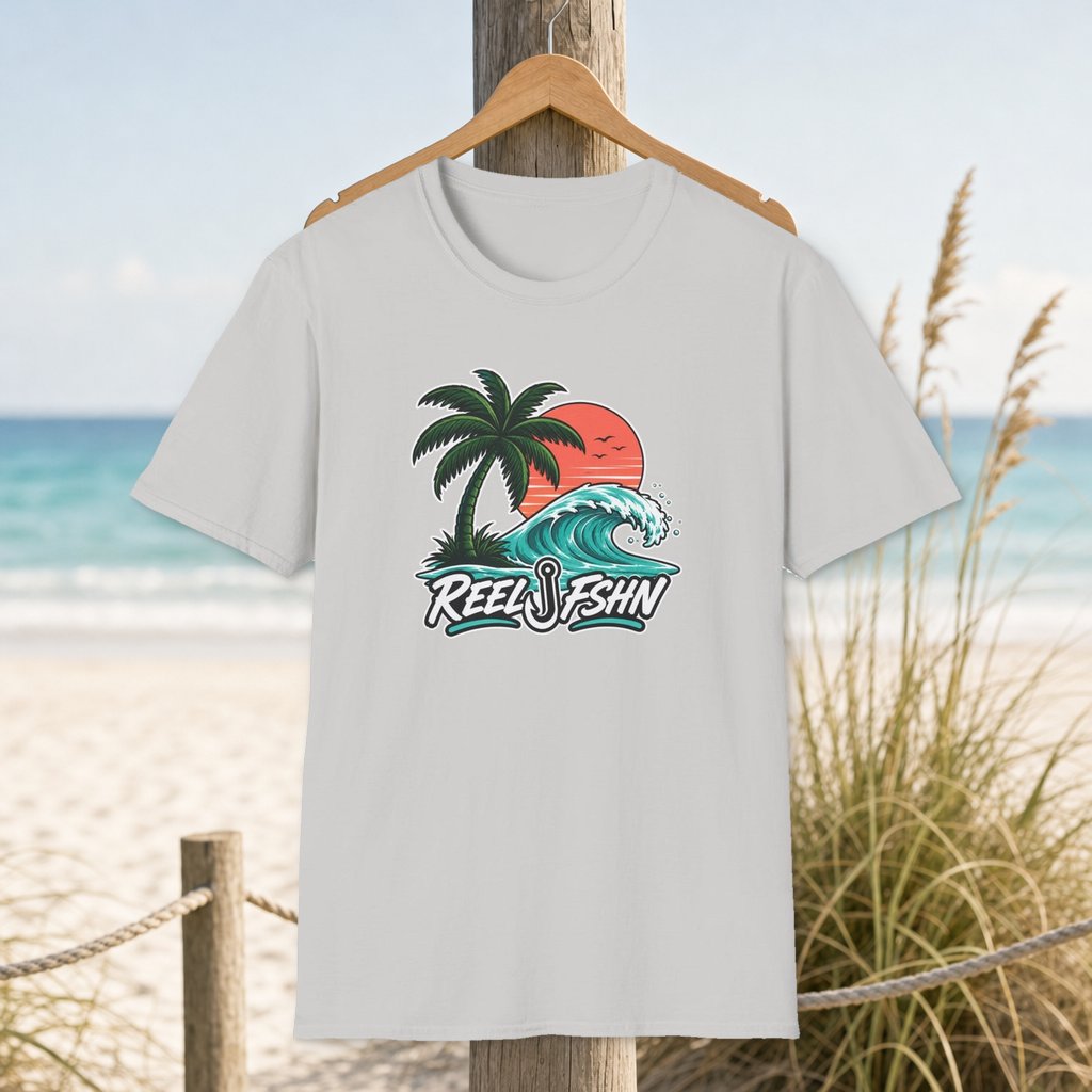 Palm & Turquoise Wave T-Shirt on a hanger beside a sandy beach and turquoise coastal water