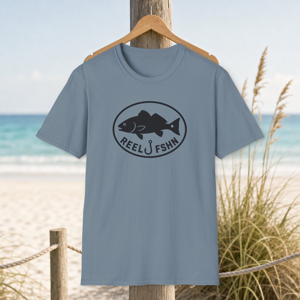Redfish Oval Badge T-Shirt on a hanger beside a sandy beach and turquoise coastal water
