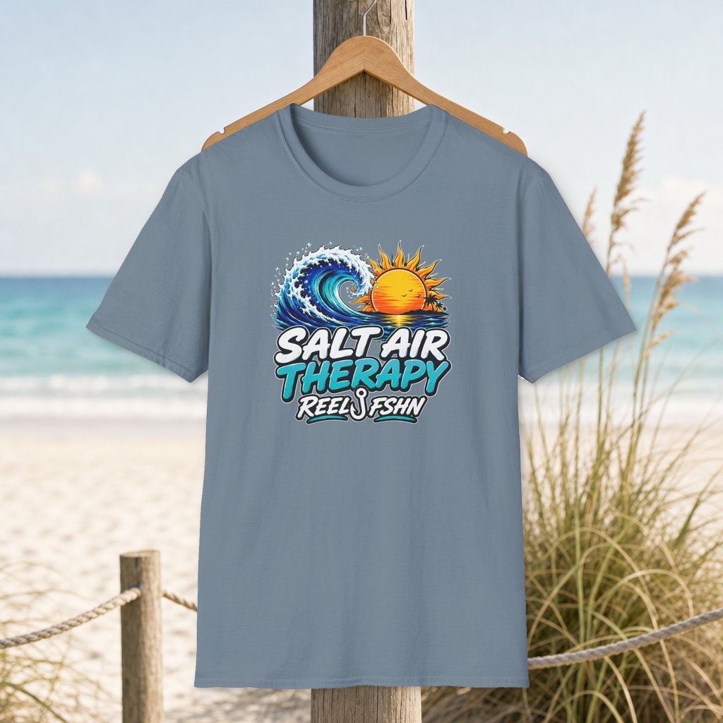 Salt Air Therapy T-Shirt on a hanger beside a sandy beach and turquoise coastal water