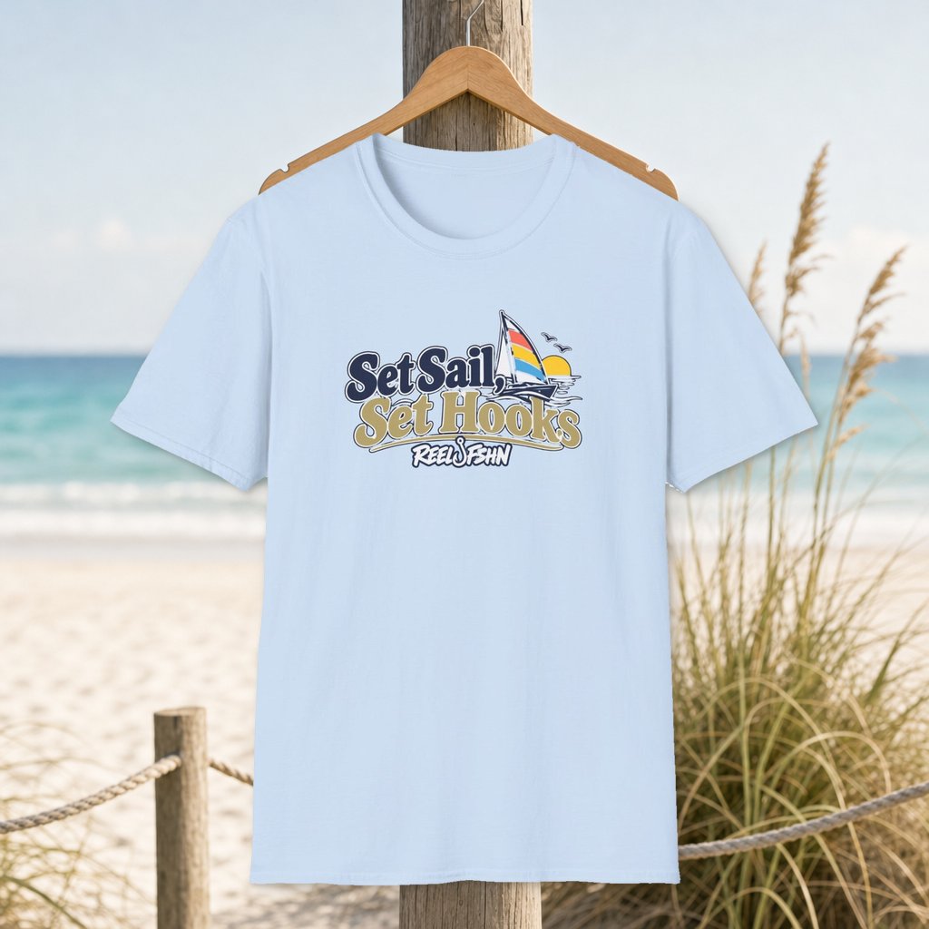 Set Sail, Set Hooks T-Shirt on a hanger beside a sandy beach and turquoise coastal water