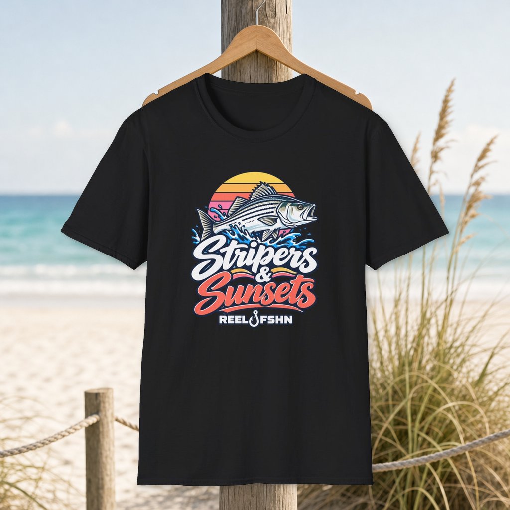 Stripers & Sunsets T-Shirt on a hanger beside a sandy beach and turquoise coastal water