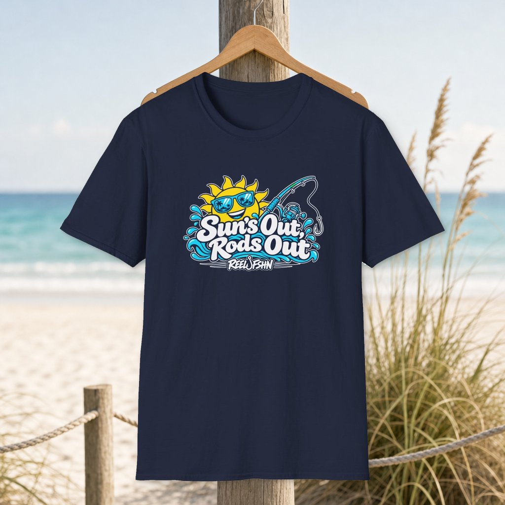 Suns Out Rods Out T-Shirt on a hanger beside a sandy beach and turquoise coastal water