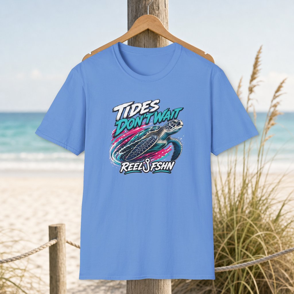 Tides Don't Wait T-Shirt on a hanger beside a sandy beach and turquoise coastal water
