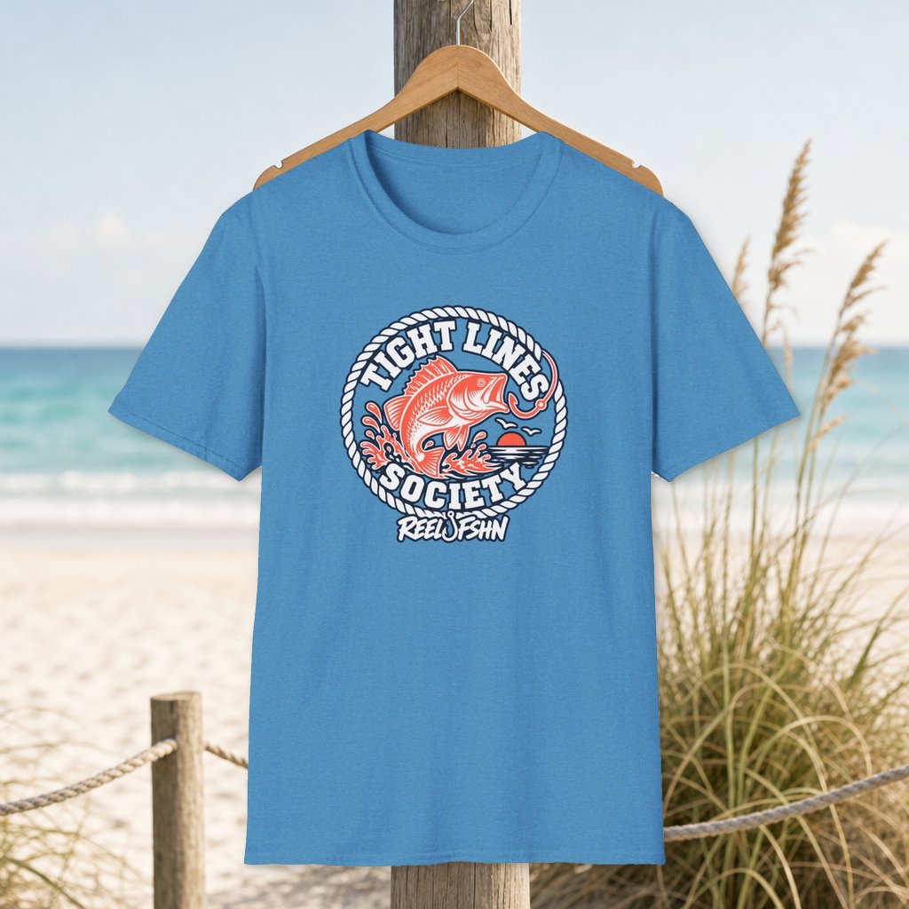 Tight Lines Society T-Shirt on a hanger beside a sandy beach and turquoise coastal water