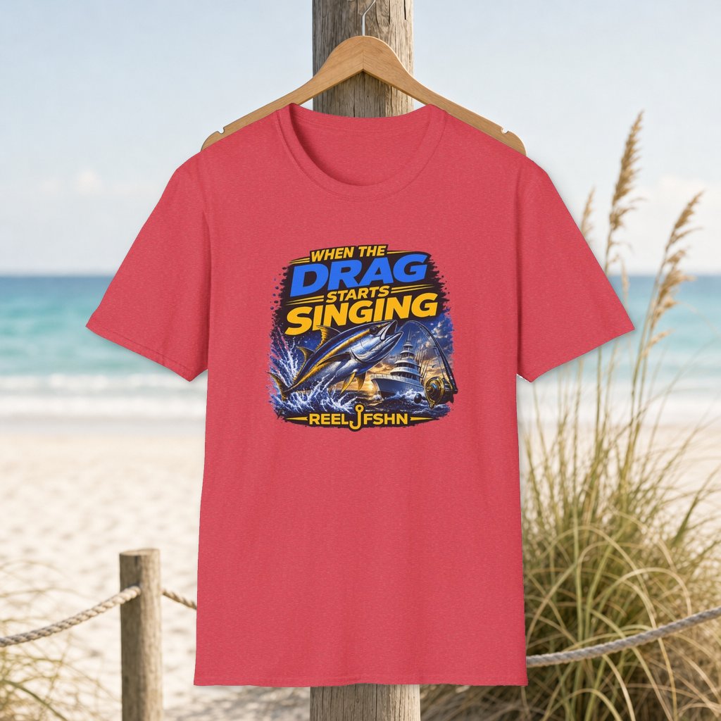 When The Drag Starts Singing T-Shirt on a hanger beside a sandy beach and turquoise coastal water