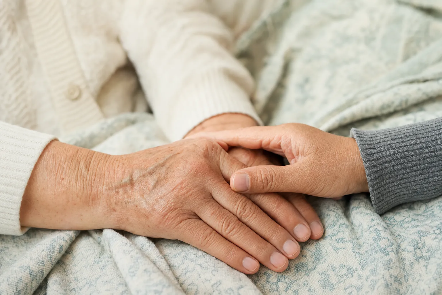 Two people resting their hands together on a soft blanket