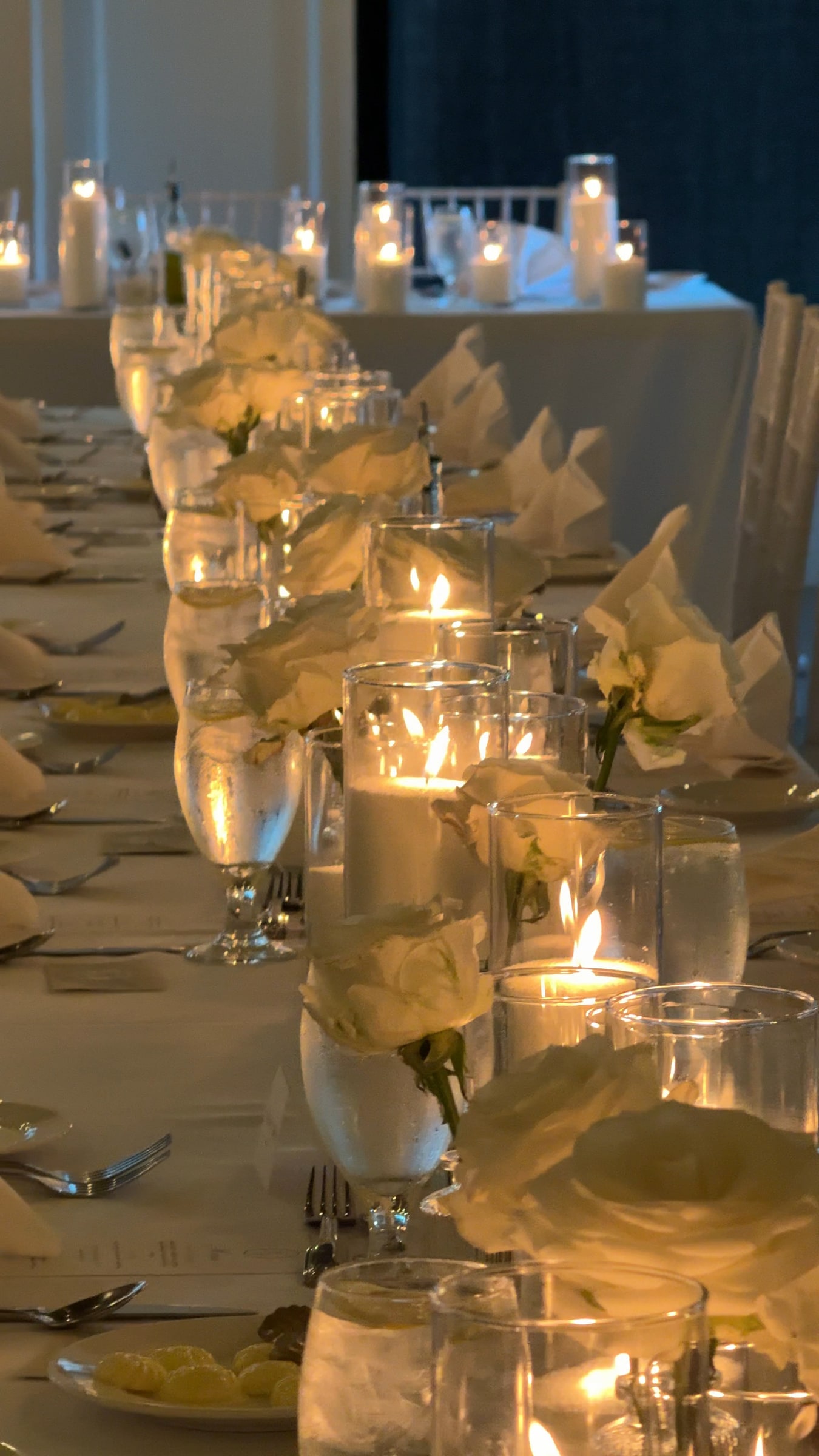 Candlelit reception table with white roses and glass cylinder candlelight